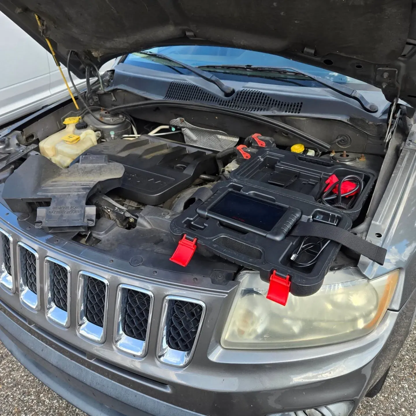 Autel diagnostic scan tool resting on the open hood of a Jeep